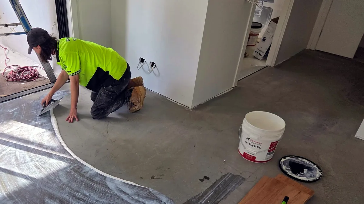 Bailey on site spreading adhesive before laying flooring