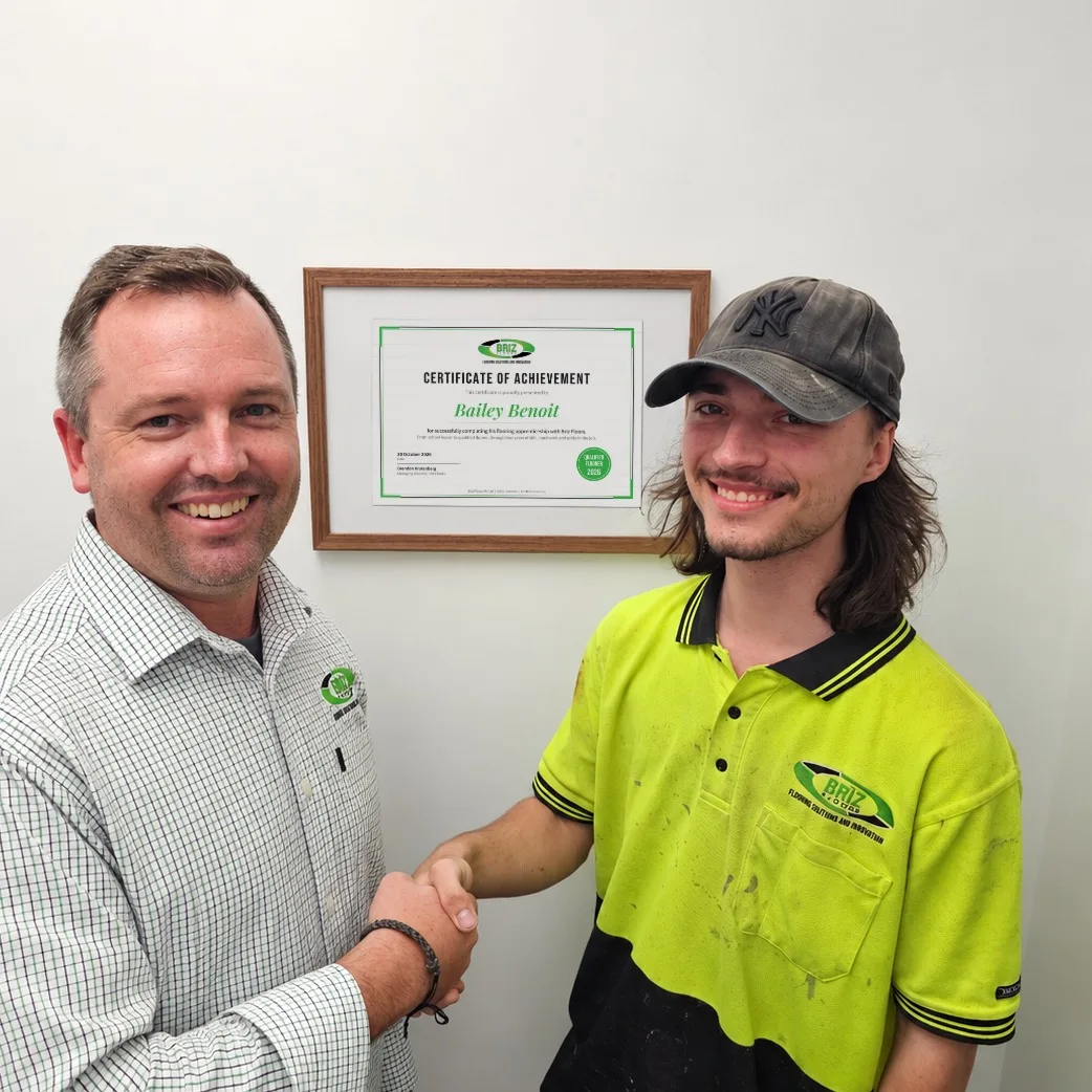 Brendon Krytenberg shaking hands with Bailey in front of his framed certificate
